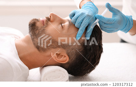 Side view of handsome middle aged man getting hair treatment at beauty salon. Man having mesotherapy session at aesthetic clinic, therapist hands in gloves making injection in scalp, closeup 120317312