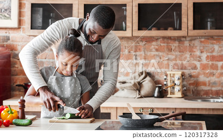 Cheerful African Man Showing His Lovely Daughter How To Cut Cucumber, cooking together at kitchen, copy space 120317328