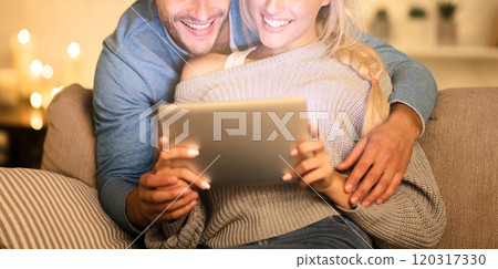Preparation for xmas. Loving couple searching gifts on tablet, spending cold evening at home 120317330