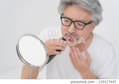 Middle-aged gray-haired man shaving his beard 120317445