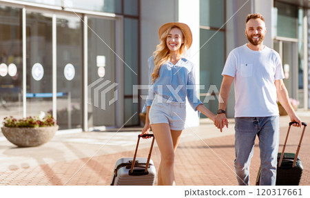 Full Of Joy Concept. Excited tourists walking near airport terminal, carrying valises and holding hands, copy space Full Of Joy Concept. Excited tourists walking near airport terminal, carrying valises and holding hands, copy space 120317661