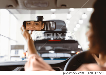 New Car Concept. Happy Afro Girl Checking Mirrors Sitting In Driver's Seat Testing Buying Auto In Dealership Store. Selective Focus 120317720