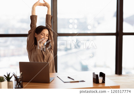 Good Morning. Happy female manager stretching her body and arms working at home or modern office, copyspace Good Morning. Happy female manager stretching her body and arms working at home or modern office, copyspace 120317774