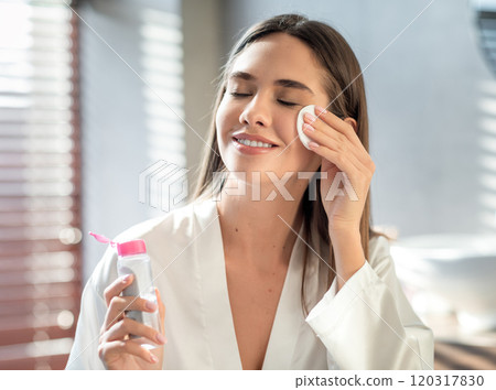 Beautiful Smiling Woman Cleansing Skin With Micellar Water And Cotton Pad While Making Daily Beauty Routine In Bathroom, Attractive Young Female Enjoying Home Skincare Treatments, Copy Space Beautiful Smiling Woman Cleansing Skin With Micellar Water And Cotton Pad While Making Daily Beauty Routine In Bathroom, Attractive Young Female Enjoying Home Skincare Treatments, Copy Space 120317830