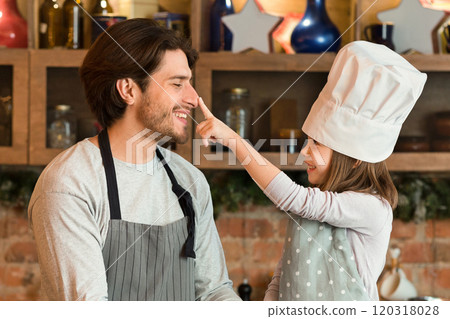 Baking Fun. Happy Little Girl And Her Dad Fooling Together While Cooking In Kitchen, Preparing Homemade Pastry, Cute Daughter In Chef's Hat Playfully Touching Father's Nose, Copy Space 120318028