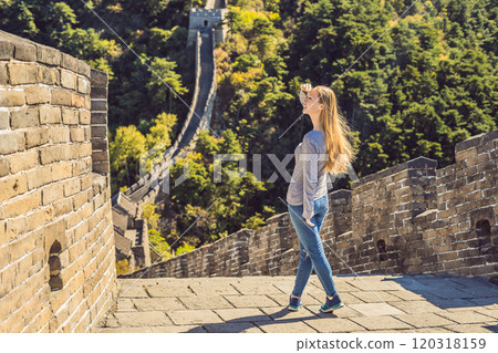 Happy cheerful joyful tourist woman at Great Wall of China having fun on travel smiling laughing and dancing during vacation trip in Asia. Girl visiting and sightseeing Chinese destination 120318159