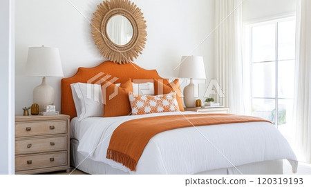 A white bedroom with large windows and white curtains. A bed with white linens and an orange headboard is made with orange pillows and a blanket 120319193