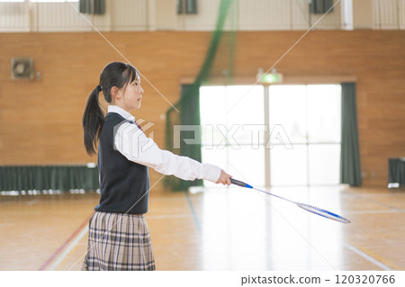 A girl holding a badminton racket in a gym 120320766