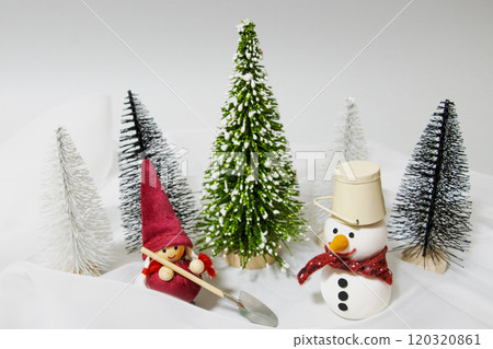 A girl with a shovel and a snowman wearing a bucket 120320861