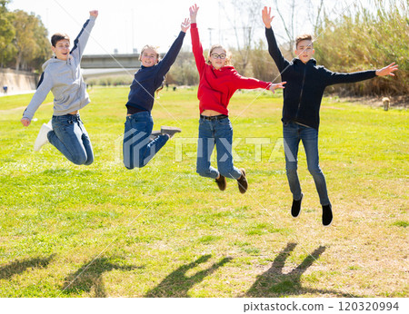 Four joyful teens jump on a lawn 120320994