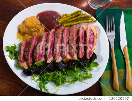 Top view of sliced duck magret with sauces, prune 120320997