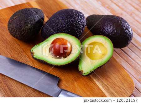 Whole and halved avocados on wooden cutting board Whole and halved avocados on wooden cutting board 120321157