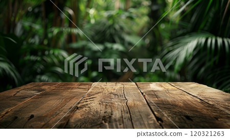 A close-up of a wooden table with a blurred background of lush green tropical foliage. 120321263