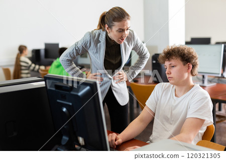 Strict teacher reprimanding negligent teenage student in computer class Strict teacher reprimanding negligent teenage student in computer class 120321305