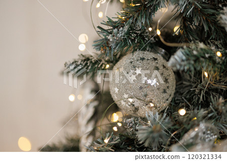 Close-up of a Christmas tree against a background of blurry garland lights. 120321334