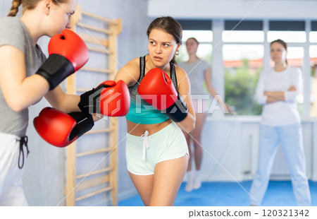 Teen girls in punch mitts boxing Teen girls in punch mitts boxing 120321342