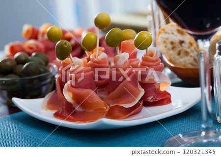 Traditional Spanish tapas - rolls of jamon serrano served with green olives 120321345
