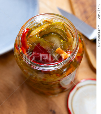 Open jar of pickled cucumber salad with peppers and carrots Open jar of pickled cucumber salad with peppers and carrots 120321389