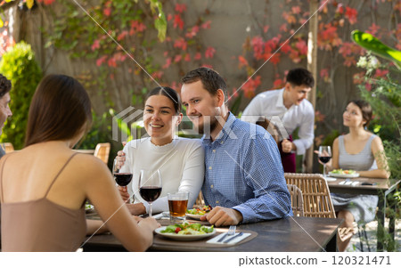 Meeting of two married couples in cozy open-air restaurant 120321471