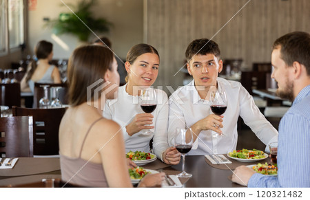 Two couples meet for dinner at restaurant. They chat and drink wine Two couples meet for dinner at restaurant. They chat and drink wine 120321482