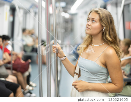 Young woman is standing in subway car with headphones Young woman is standing in subway car with headphones 120321605
