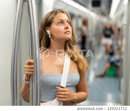 Young woman with headphones standing in metro car 120321712