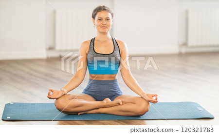 Lover of active lifestyle on yoga mat perform doing variations of padmasan in gym Lover of active lifestyle on yoga mat perform doing variations of padmasan in gym 120321783