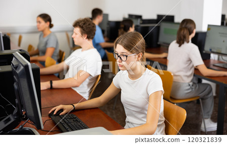 Focused female student in glasses using PC and studying computer science in the classroom 120321839