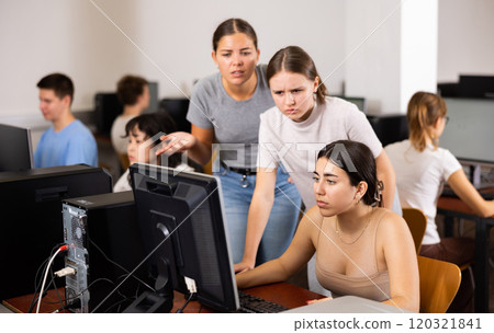 Clever students explaining the topic to female friend while she is studying computer science on the PC in the classroom Clever students explaining the topic to female friend while she is studying computer science on the PC in the classroom 120321841