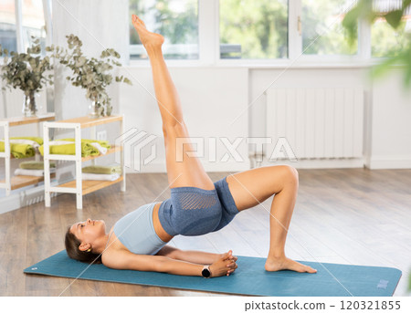Sportive girl practicing bridge pose of yoga in light room Sportive girl practicing bridge pose of yoga in light room 120321855