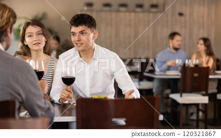 Couple and adult man eating and talking in restaurant 120321867