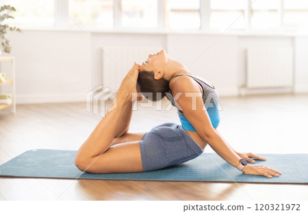 Young woman practicing yoga in dhanurasana pose 120321972