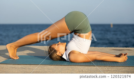 Girl practitioner of yoga performing challenging headstand, maintaining poised control and showcasing flexibility on seashore Girl practitioner of yoga performing challenging headstand, maintaining poised control and showcasing flexibility on seashore 120321974