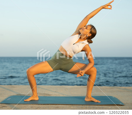 On windy day young slender woman does yoga near sea doing utkata konasana On windy day young slender woman does yoga near sea doing utkata konasana 120322035