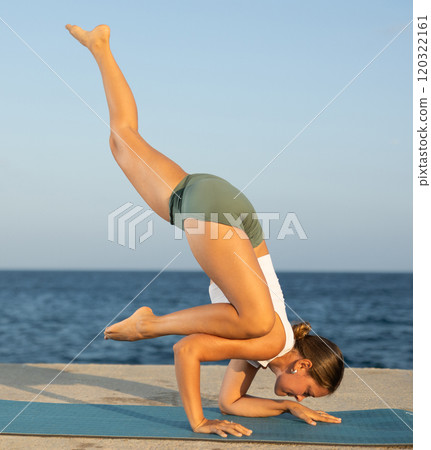 On windy day young slender woman does yoga near sea doing bakasana On windy day young slender woman does yoga near sea doing bakasana 120322161
