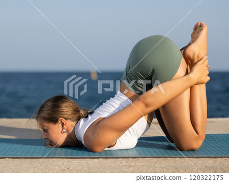 Yoga training on seashore - girl in dog pose on mats 120322175