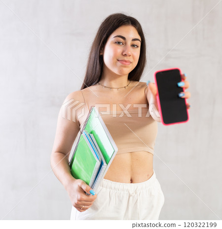 Young woman posing with stack of notebooks and phone in studio Young woman posing with stack of notebooks and phone in studio 120322199