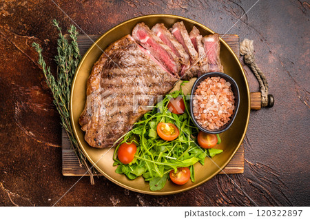 Grilled New York strip steak, beef meat steak on a plate with salad. brown background. top view 120322897