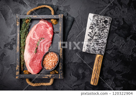 Raw New York strip beef steak in a wooden tray with herbs. black background. top view Raw New York strip beef steak in a wooden tray with herbs. black background. top view 120322904