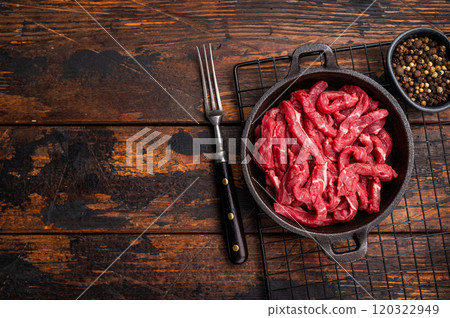 Raw beef meat sliced strips for beef stroganoff in a skillet. wooden background. top view 120322949