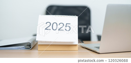 2025 Year Calendar on table with laptop computer during working and writing in office. countdown, Happy New Year, Resolution, Year End and New Start and Goals Plan Action Concept 120326088