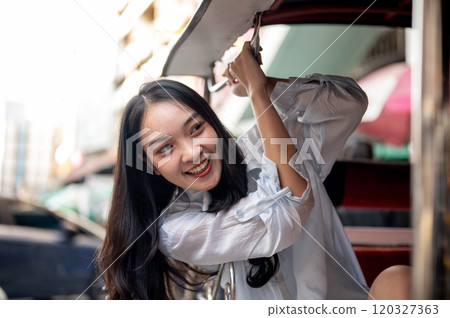 A beautiful Asian female tourist enjoying a ride in a tuk-tuk in Thailand, looking at the views. 120327363