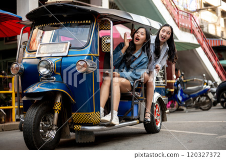 Two excited Asian girls enjoy a ride in a tuk-tuk in Thailand, amazed by the stunning views. 120327372