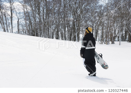 A young woman standing with a snowboard looking at the camera Snowboard image A young woman standing with a snowboard looking at the camera Snowboard image 120327446