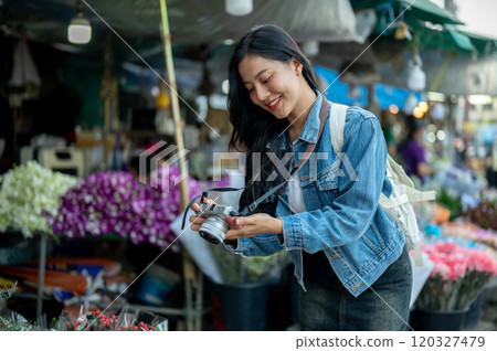 A beautiful Asian woman enjoys strolling through a flower market in Thailand. A beautiful Asian woman enjoys strolling through a flower market in Thailand. 120327479