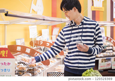A young man shopping at a supermarket with a smartphone in hand A young man shopping at a supermarket with a smartphone in hand 120328369