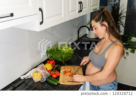 Pregnant woman preparing meal on kitchen island from fresh ingredients Pregnant woman preparing meal on kitchen island from fresh ingredients 120328712