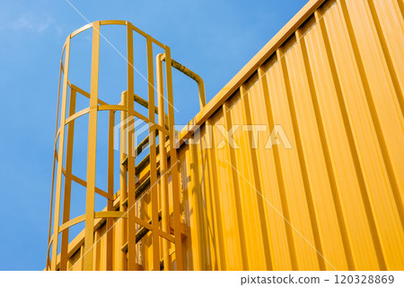 Fire escape stairs Made of steel on buildings are constructed with metal sheet material painted in yellow throughout with a background of a blue sky during the day. Fire escape stairs Made of steel on buildings are constructed with metal sheet material painted in yellow throughout with a background of a blue sky during the day. 120328869