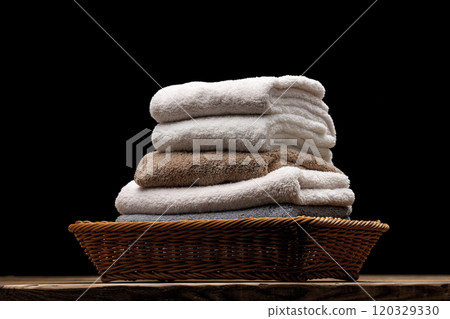 Folded and stacked towels in a basket on a black background Folded and stacked towels in a basket on a black background 120329330