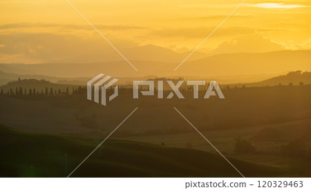 Golden sunset over rolling hills and distant mountains 120329463